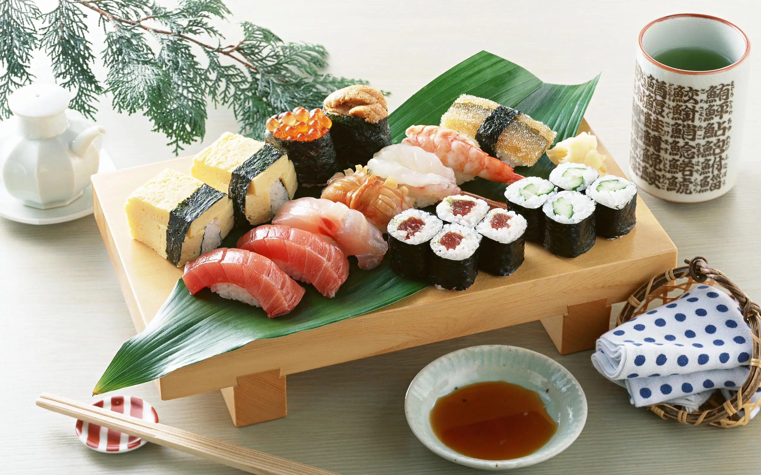 sushis variés servis sur plateau bois avec thé vert et sauce soja