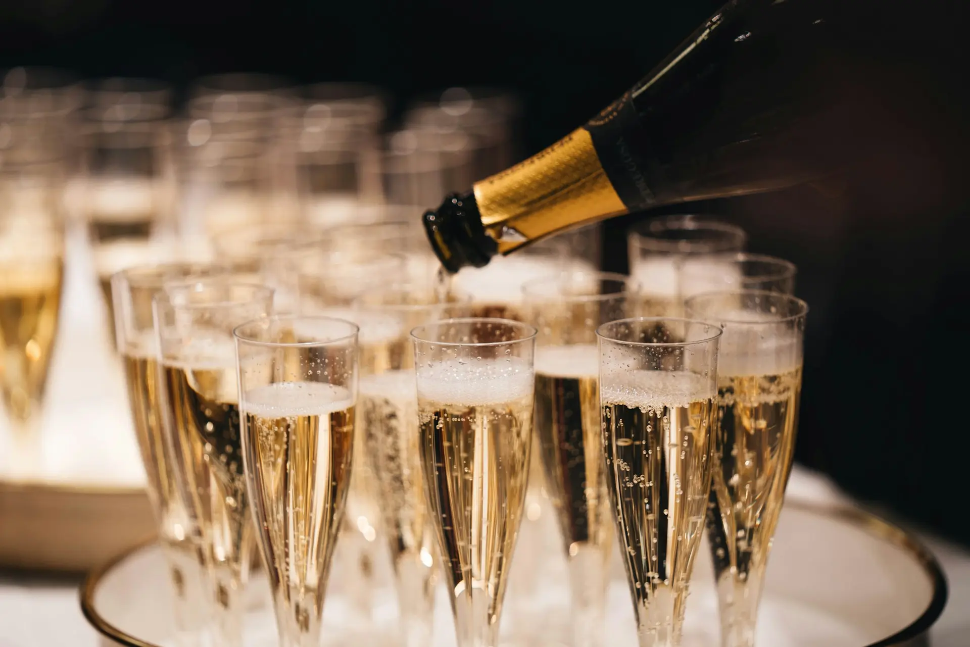 champagne versé dans des flûtes pour un mariage, bouteille dorée et bulles