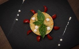 Couscous dish creatively plated with basil and cherry tomatoes on a slate plate.