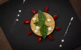 Couscous dish creatively plated with basil and cherry tomatoes on a slate plate.