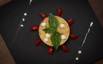 Couscous dish creatively plated with basil and cherry tomatoes on a slate plate.