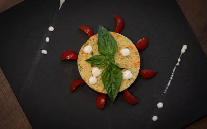 Couscous dish creatively plated with basil and cherry tomatoes on a slate plate.