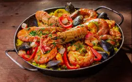 A vibrant and flavorful seafood paella served in a pan with mussels and shrimp.