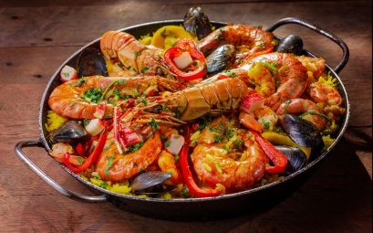 A vibrant and flavorful seafood paella served in a pan with mussels and shrimp.